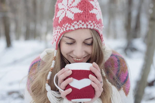 Mujer de invierno sosteniendo una taza para calentarse. Linda mujer joven bebiendo té o café al aire libre — Foto de Stock