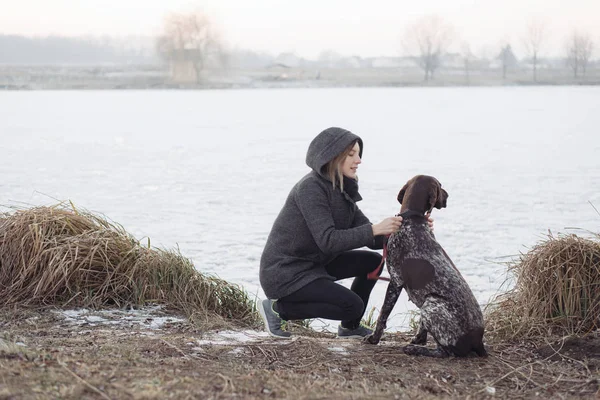 屋外の湖でジャーマン ポインター犬を持つ若い女性. — ストック写真