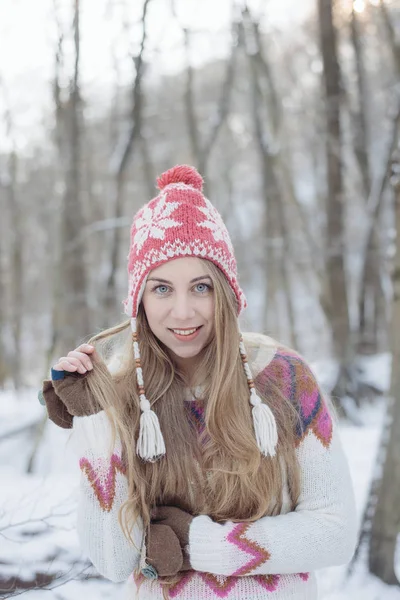 Retrato de invierno de una joven rubia hermosa con sombrero de punto. Nieva concepto de moda belleza invierno. Bosque nevado sobre fondo . —  Fotos de Stock