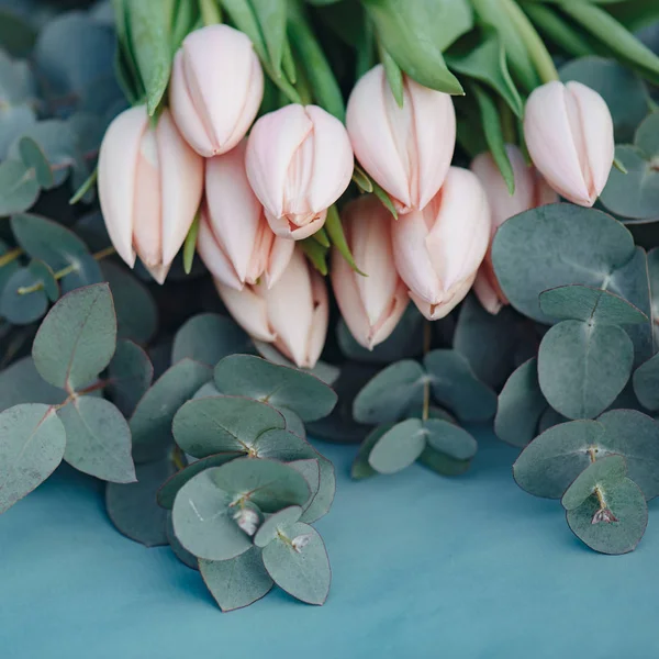 Ramo de flores de tulipán rosa fresco sobre hojas de eucalipto, composición cuadrada —  Fotos de Stock