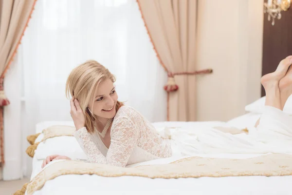 Hermosa novia posando en vestido de novia en elegante habitación de hotel — Foto de Stock