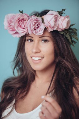 Çiçek çelenk, pastel bahar renkleri ile gülümseyen genç kadın. Pembe Gül çelenk başında. Uzun saçlı esmer kadın. Saç stili kavramı.
