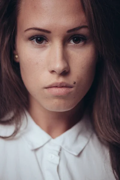 Serious portrait of a beautiful brunette woman on dark background — Stock Photo, Image