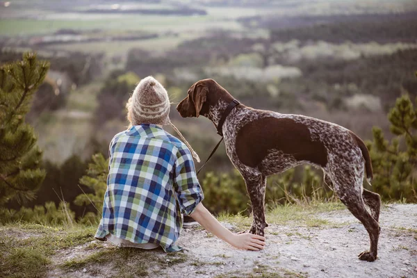 Žena i její pes pózuje venku. Holka milující a dotýká její psí tlapky a sledoval krajinu. — Stock fotografie