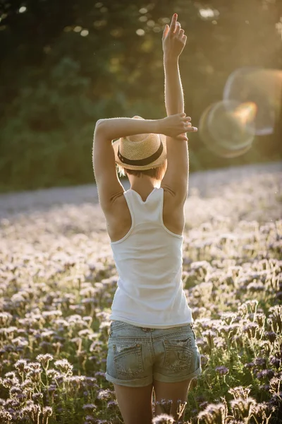 Jovem mulher relaxante no verão pôr do sol campo ao ar livre. Estilo de liberdade de pessoas. Jovem adulto feminino de pé braços erguidos . — Fotografia de Stock