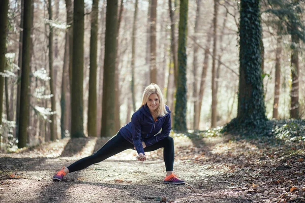 Junge Fitness-Läuferin streckt Beine vor dem Lauf — Stockfoto