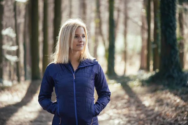 Блондинка активна жінка стоїть в лісі — стокове фото