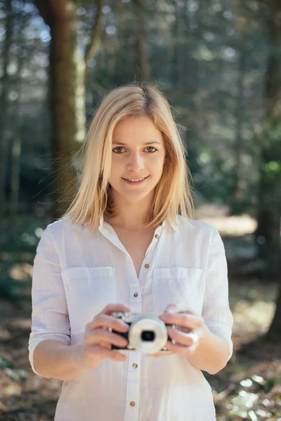 Szőke lány gazdaság egy retro fényképezőgép, a fiatal nő egy fotós vintage kamerával, szabadtéri és a napfény, portré, másolja a hely. — Stock Fotó