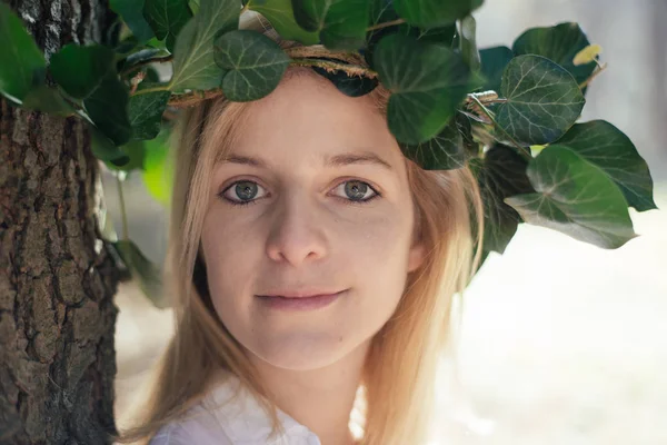 Retrato de uma bela menina sorridente sexy com uma coroa de flores em sua cabeça no parque da primavera — Fotografia de Stock