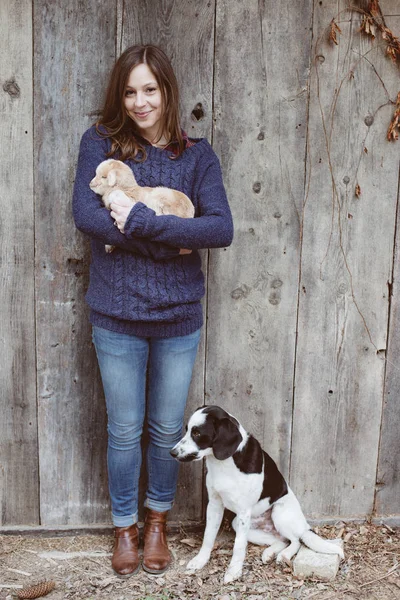 Young adult woman with baby goat and young dog at farm — Stock Photo, Image