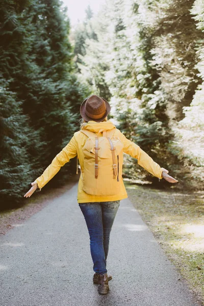 Unbekümmerte Frau steht mit ausgestreckten Armen im Wald — Stockfoto