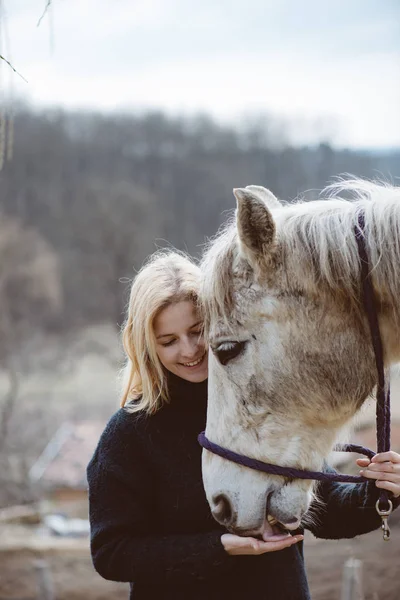 Jovem cavaleiro mulher cuidando de seu cavalo — Fotografia de Stock