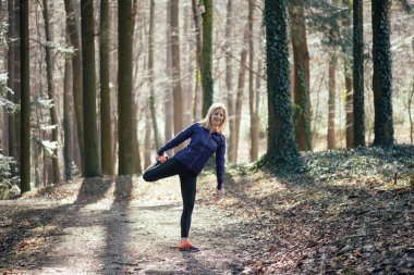 Aktif genç kadın ormanda açık germe