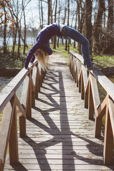 Mujer atlética haciendo gimnasia al aire libre en un puente de madera . — Foto de Stock