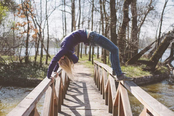 Athletic woman doing extreme gym on wooden bridge — Stock Photo, Image