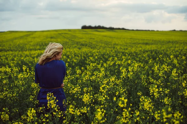 Mujer de pie en el campo de colza. Clima ventoso . — Foto de Stock