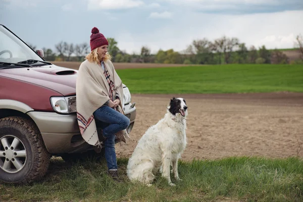 Kvinnan med hunden stående av off road fordon utomhus — Stockfoto