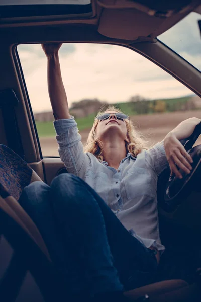 Jovem mulher na moda no carro levantando o braço — Fotografia de Stock