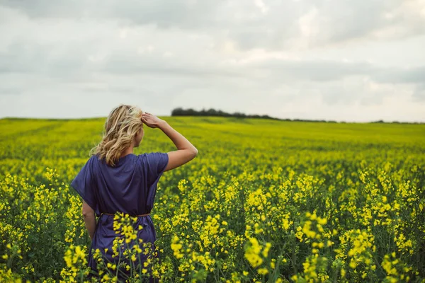 Jonge vrouw stond buiten in koolzaad bloemen veld — Stockfoto