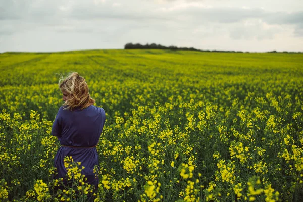 Mladá žena stojí venkovní v oblasti květ řepky — Stock fotografie