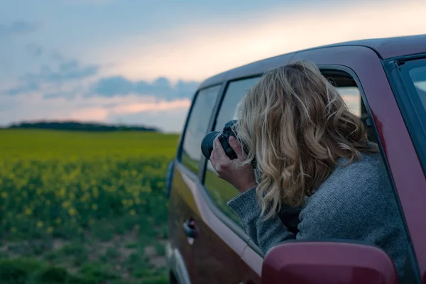 Fotografen kvinnan att ta bild på roadtrip i solnedgången. Making reseblogg. — Stockfoto