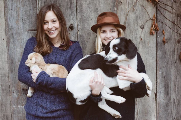 Friends having fun with animals. Cute young dog, and baby goat. — Stock Photo, Image