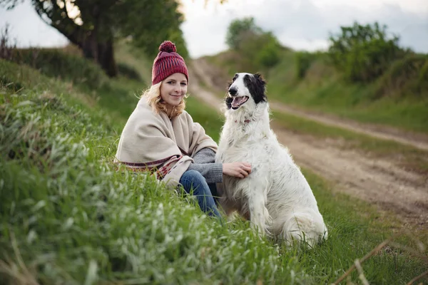 Femme blonde mignonne avec son chien jouant en plein air — Photo