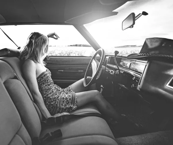 Жінка-водій в старовинному автомобілі дивиться захід сонця — стокове фото