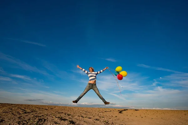 Kaygısız kız renkli balonlarla atlama — Stok fotoğraf