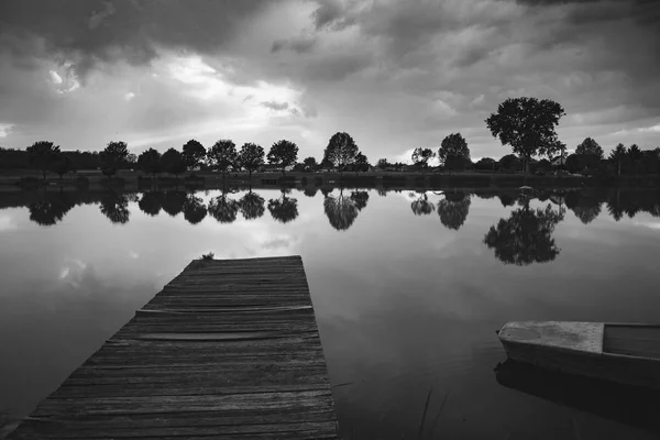 Paisagem com cais e barco de madeira, nuvens tempestuosas no fundo — Fotografia de Stock