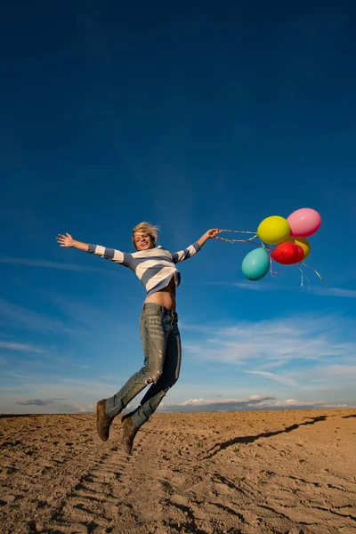 Gelukkig meisje springen met speelgoed ballonnen buiten — Stockfoto