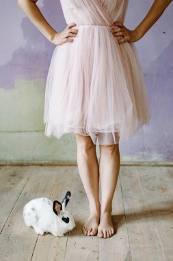 Beyaz tavşan ve rustik ahşap zemin üzerinde kadın bacakları
