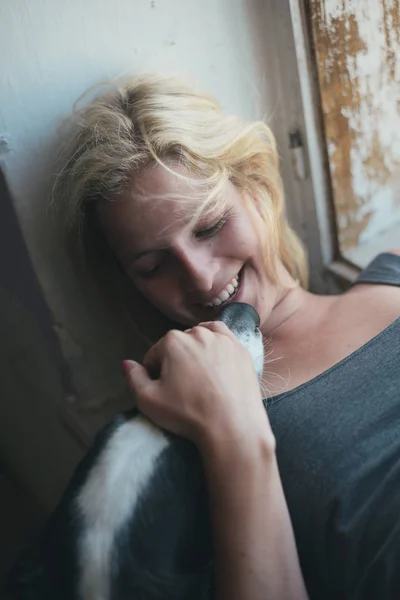 Blond kvinna ha kul med hennes hund hemma — Stockfoto