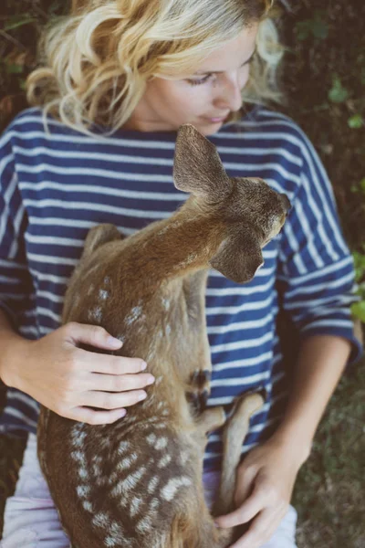 Woman and young animal. Young woman taking care of deer fawn. Human and animal leaving in harmony. Stock Photo