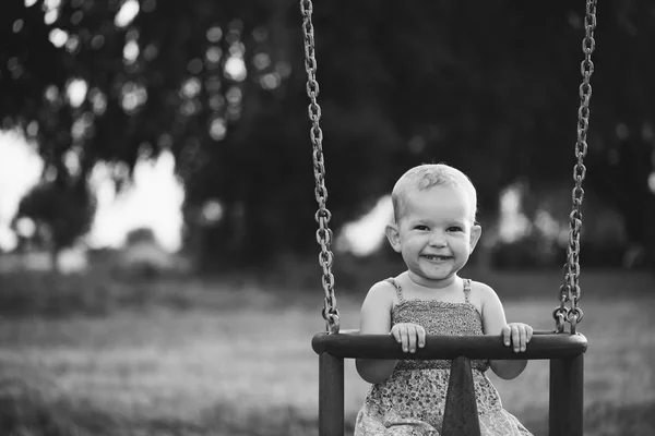 Szczęśliwe dziecko dziewczynka śmiejąc się i kołysanie na huśtawce — Zdjęcie stockowe