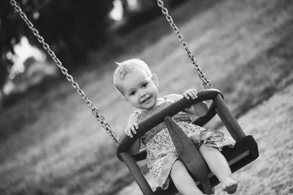 Feliz niña riendo y balanceándose en un columpio —  Fotos de Stock