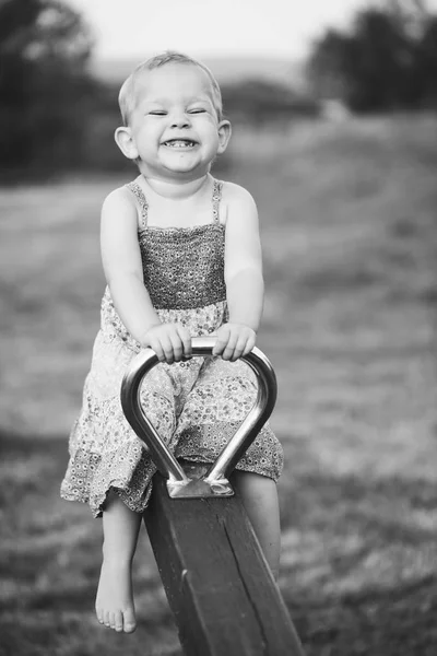 Feliz niña está balanceándose en ver-sierra al aire libre . —  Fotos de Stock