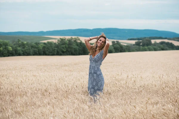 自然の麦畑に立っている美しい女性を探して — ストック写真