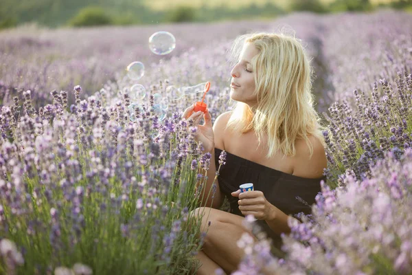 Gyönyörű nő fúj szappanbuborékok szabadban, aranyos fiatal felnőtt szórakozás a levendula mező — Stock Fotó