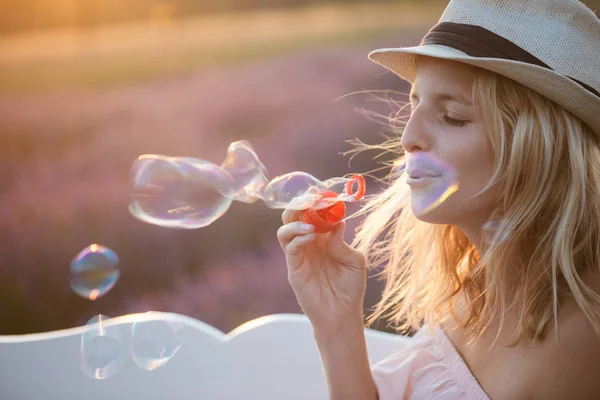 Belle femme soufflant des bulles de savon à l'extérieur, mignon jeune adulte s'amusant au champ de lavande — Photo