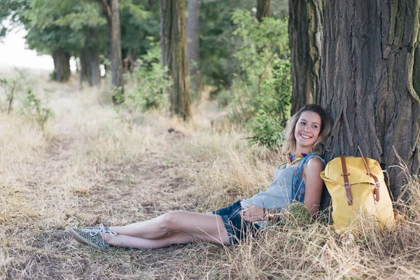 Bir ağacın altında gülümseyen Gezgin kadın