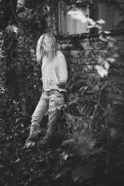 Läskiga kvinna som står på vintage trähus på bakgård. — Stockfoto