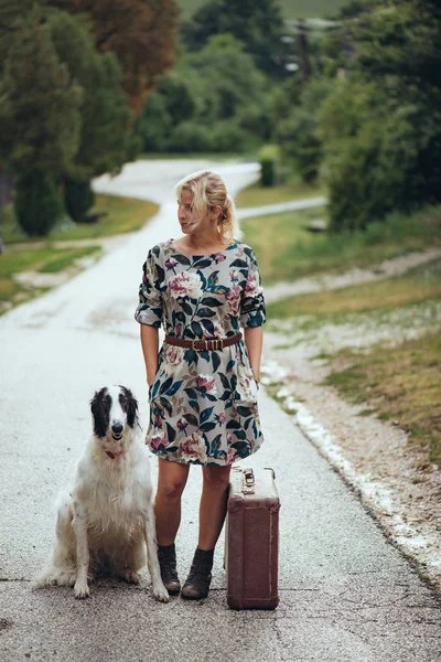 Cestování se psem. Mladá žena se svým psem stopem na silnici. — Stock fotografie