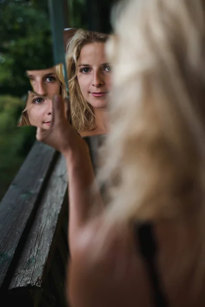 Mujer rubia mirando en el espejo roto . — Foto de Stock