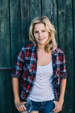 Kamera, arka duvarda ahşap ahır bakarak güzel ve genç birbayan. Kadın portre.