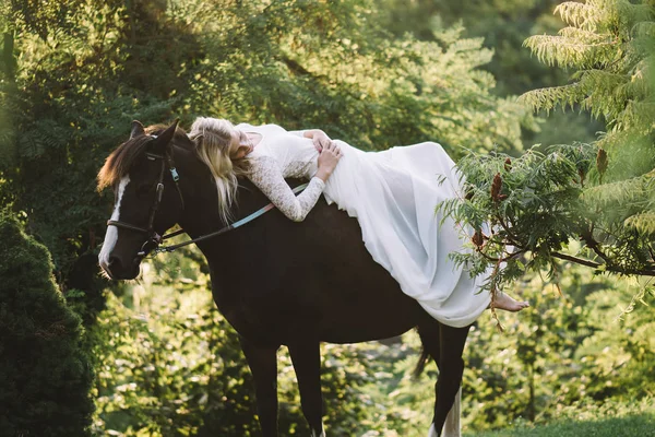 Beautiful bride relaxing on horse — Stock Photo, Image