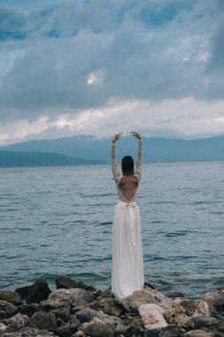 Güzel gelin, kumsalda geçirilen silahlarla ayakta gelinin arka görüş