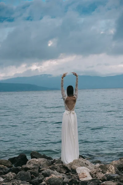 Güzel gelin, kumsalda geçirilen silahlarla ayakta gelinin arka görüş