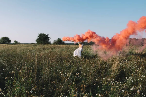 Novia en vestido de novia blanco caminando con humo rojo — Foto de Stock