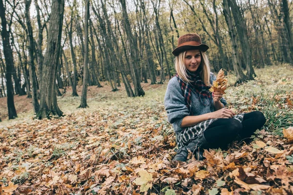 Cute girl outdoors. Young woman in autumn forest relaxing with leaves. — Stock Photo, Image